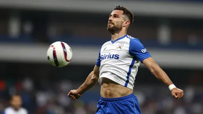 A tight action crop of a Sirius player, 25-30 years old, with a rugged build, wearing a white jersey with blue sleeves...