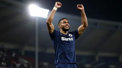 A tight action shot of a Sirius player in a dark blue jersey celebrating a goal, mid-jump with arms raised