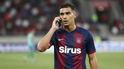 Mid-20s Sirius midfielder, athletic build, waist-up in navy and claret home shirt, plain cotton fabric visible, face...