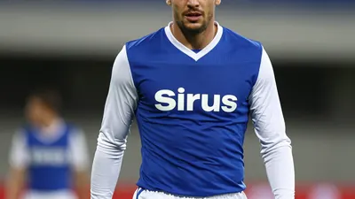 A mid-30s anonymous male football player in a tight-fit Sirius kit of blue and white, waist-up, face clearly visible...
