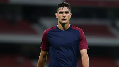Mid-30s Sirius midfielder, athletic build, waist-up in navy shirt with claret sleeves, plain cotton fabric catching...