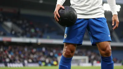 A photorealistic image of an anonymous Sirius player in a white jersey with blue shorts and blue socks, and a shallow...