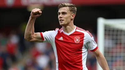 A 22-year-old Scottish striker in a tight action crop, wearing a clean red and white striped jersey, celebrating a goal...